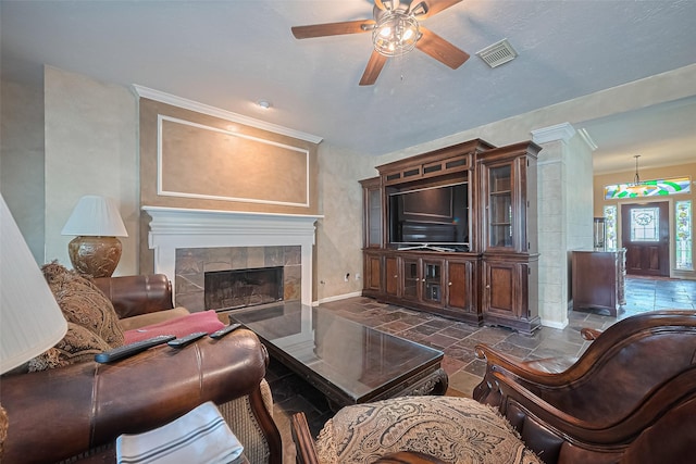 15014 Redbud Leaf Ln, Cypress, TX 77433 - living area featuring ceiling fan, stone tile flooring, a tiled fireplace, and ornamental molding