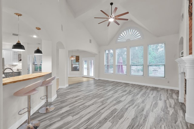 28315 Hollow Springs Ln, Spring, TX 77386 - unfurnished living room featuring arched walkways, ceiling fan, light wood-type flooring, and high vaulted ceiling