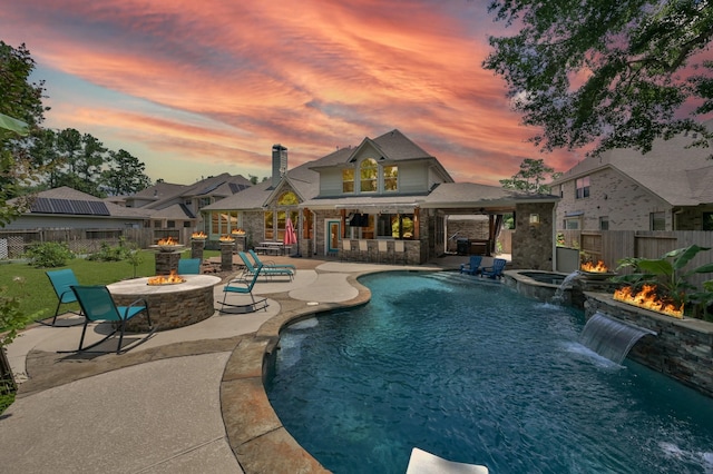 28315 Hollow Springs Ln, Spring, TX 77386 - pool at dusk featuring a fire pit, a fenced backyard, a patio, exterior bar, and a pool with connected hot tub