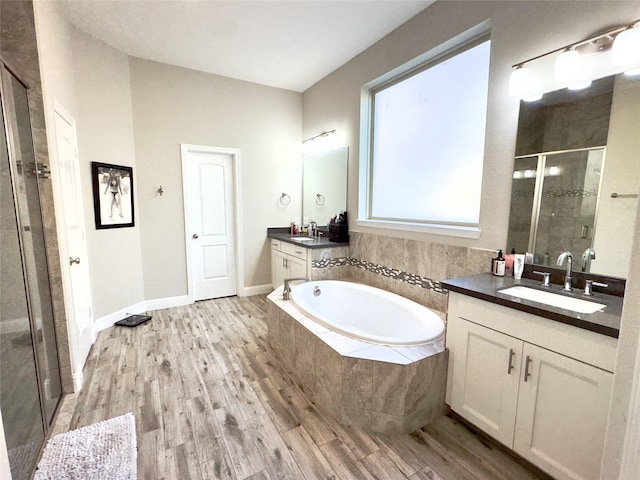 9723 Reston Ranch Ct, Cypress, TX 77433 - full bath with wood finished floors, a stall shower, two vanities, and a garden tub