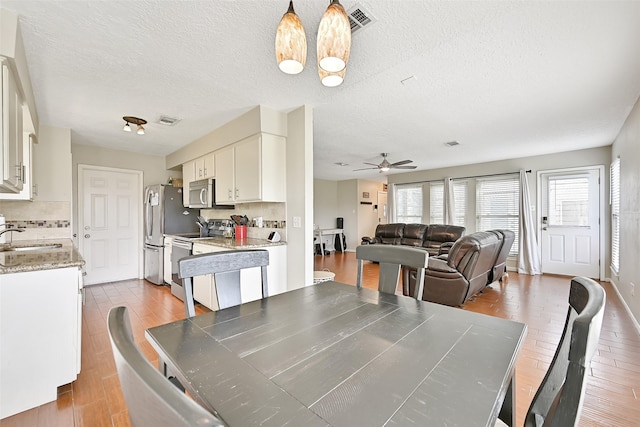 17202 Heritage Bay Dr, Webster, TX 77598 - dining room featuring ceiling fan, dark wood-type flooring, a chandelier, a textured ceiling, and baseboards