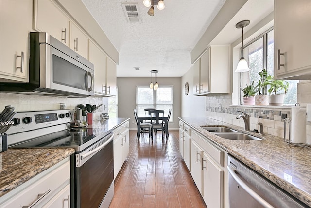 17202 Heritage Bay Dr, Webster, TX 77598 - kitchen with appliances with stainless steel finishes, a sink, pendant lighting, backsplash, and light stone countertops