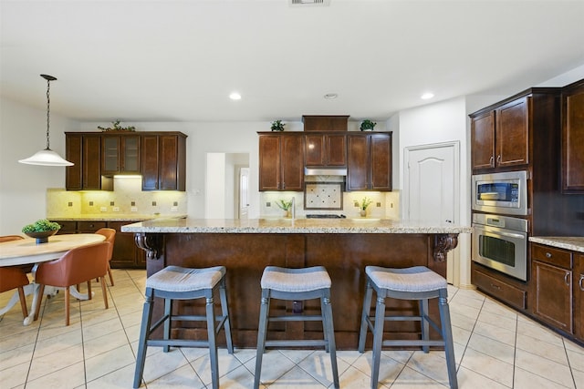 19014 Ridge Cove Ln, Cypress, TX 77433 - kitchen with appliances with stainless steel finishes, under cabinet range hood, backsplash, a breakfast bar area, and recessed lighting