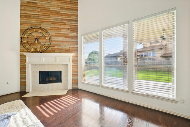 19014 Ridge Cove Ln, Cypress, TX 77433 - unfurnished living room featuring a high ceiling, a tiled fireplace, dark wood-style floors, wood walls, and baseboards