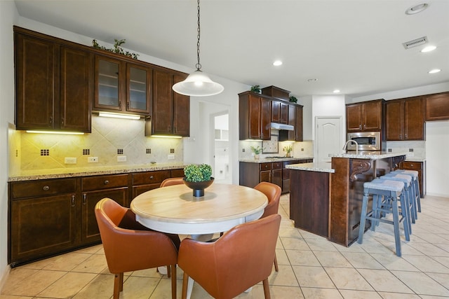 19014 Ridge Cove Ln, Cypress, TX 77433 - kitchen with stainless steel microwave, backsplash, light tile patterned floors, hanging light fixtures, and recessed lighting