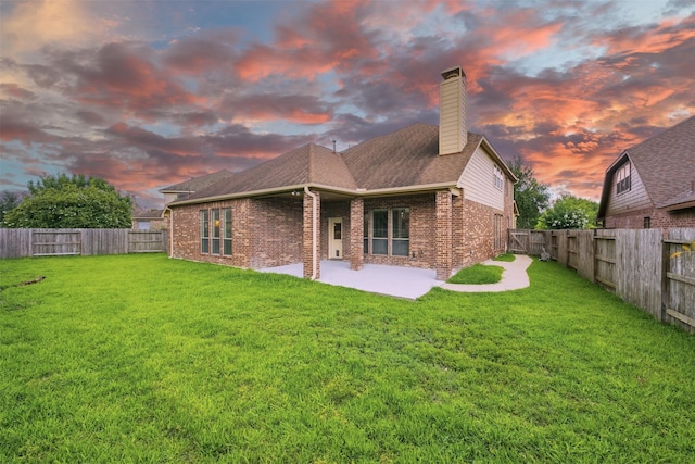 19014 Ridge Cove Ln, Cypress, TX 77433 - back of house at dusk featuring brick siding, a patio, a chimney, and roof with shingles
