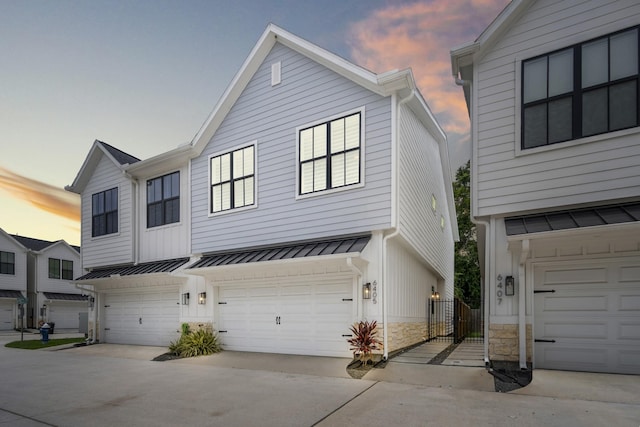 6405 Highland Pine Ln, Houston, TX 77091 - townhome / multi-family property with stone siding, driveway, a standing seam roof, a garage, and metal roof