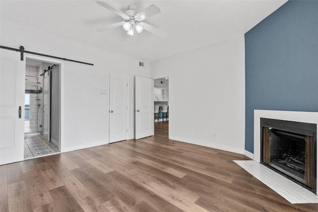 18809 Egret Bay Blvd Unit 114, Webster, TX 77058 - unfurnished living room with a barn door, a ceiling fan, wood finished floors, baseboards, and a fireplace with flush hearth