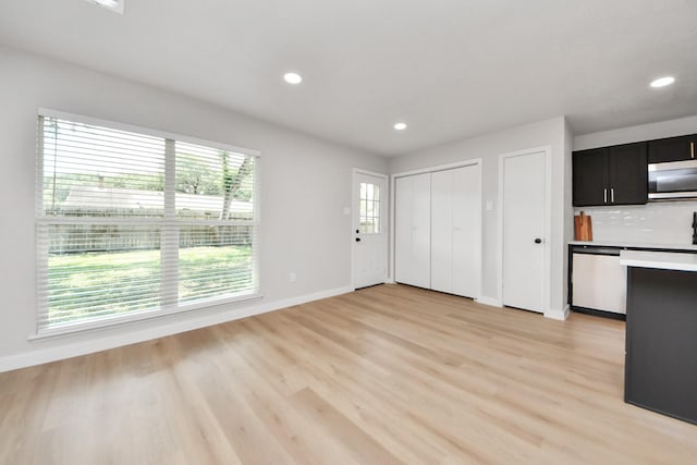 4439 Kacee Dr, Houston, TX 77084 - kitchen with appliances with stainless steel finishes, dark cabinetry, light wood finished floors, recessed lighting, and decorative backsplash