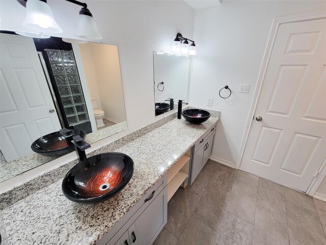 5703 Fraser Ave, Galveston, TX 77551 - full bathroom with baseboards, toilet, and double vanity