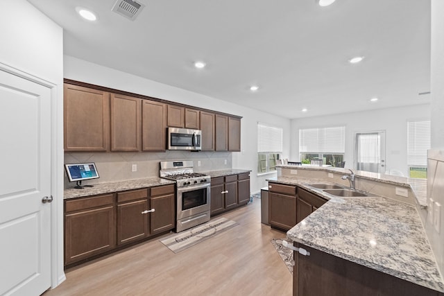 5107 Twin Summit Dr, Rosenberg, TX 77469 - kitchen featuring appliances with stainless steel finishes, a sink, light wood-type flooring, backsplash, and light stone countertops