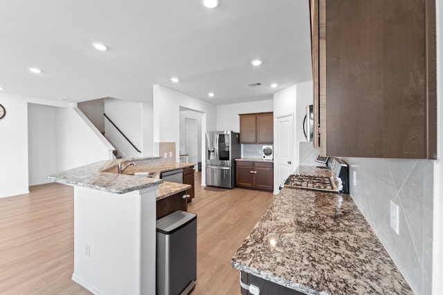 5107 Twin Summit Dr, Rosenberg, TX 77469 - kitchen with appliances with stainless steel finishes, light wood-type flooring, a sink, decorative backsplash, and light stone counters