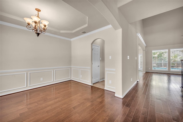 25402 Lancaster Pine Dr, Spring, TX 77389 - empty room featuring arched walkways, wood finished floors, a chandelier, ornamental molding, and a raised ceiling