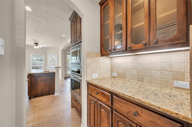 25402 Lancaster Pine Dr, Spring, TX 77389 - kitchen with appliances with stainless steel finishes, tasteful backsplash, light tile patterned floors, glass insert cabinets, and light stone counters