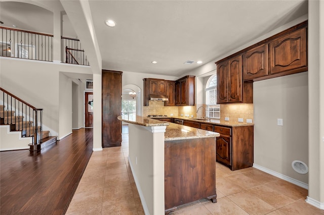 25402 Lancaster Pine Dr, Spring, TX 77389 - kitchen with under cabinet range hood, light stone countertops, tasteful backsplash, a sink, and recessed lighting