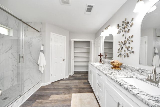 15723 Cascade Point Dr, Houston, TX 77084 - bathroom with double vanity, a marble finish shower, wood finished floors, a spacious closet, and baseboards