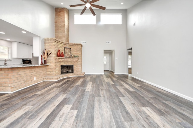 15723 Cascade Point Dr, Houston, TX 77084 - unfurnished living room featuring a ceiling fan, healthy amount of natural light, a high ceiling, wood finished floors, and a fireplace