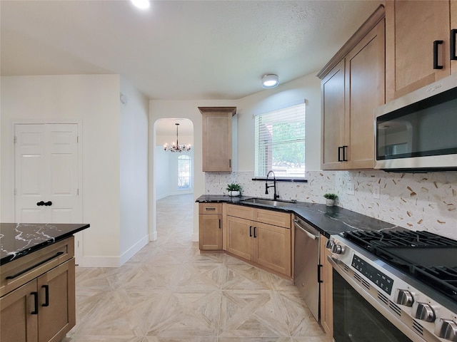 218 Windrift Ct, Sugar Land, TX 77479 - kitchen with stainless steel appliances, a sink, arched walkways, a chandelier, and decorative backsplash