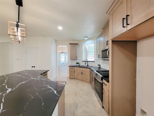218 Windrift Ct, Sugar Land, TX 77479 - kitchen featuring appliances with stainless steel finishes, a chandelier, a sink, tasteful backsplash, and dark stone counters