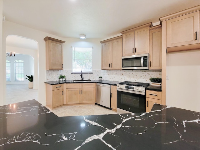 218 Windrift Ct, Sugar Land, TX 77479 - kitchen featuring appliances with stainless steel finishes, a sink, arched walkways, light brown cabinets, and tasteful backsplash