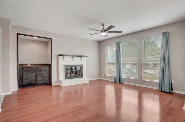 1500 Bay Area Blvd Unit 433, Houston, TX 77058 - unfurnished living room featuring a ceiling fan, wood finished floors, a brick fireplace, and baseboards