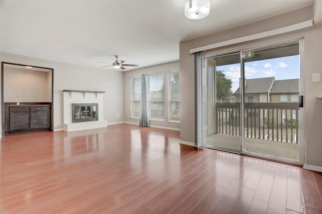 1500 Bay Area Blvd Unit 433, Houston, TX 77058 - unfurnished living room featuring ceiling fan, wood finished floors, a glass covered fireplace, and baseboards