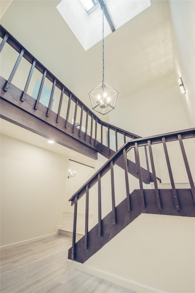12553 Wellington Park Dr, Houston, TX 77072 - stairs featuring a chandelier, wood finished floors, a towering ceiling, baseboards, and a skylight