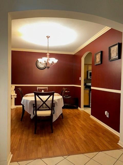 14602 Harcourt Bridge Ct, Houston, TX 77084 - tiled dining space with crown molding, arched walkways, a chandelier, and baseboards