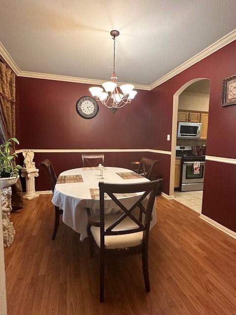 14602 Harcourt Bridge Ct, Houston, TX 77084 - dining area with a chandelier, light wood finished floors, crown molding, and arched walkways
