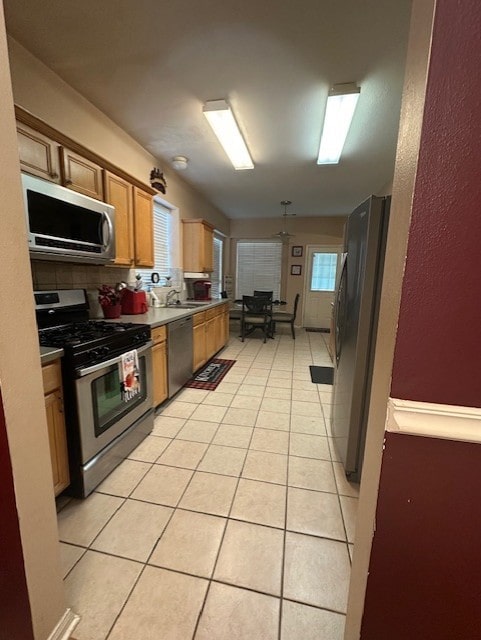 14602 Harcourt Bridge Ct, Houston, TX 77084 - kitchen with appliances with stainless steel finishes, light tile patterned flooring, a sink, and plenty of natural light