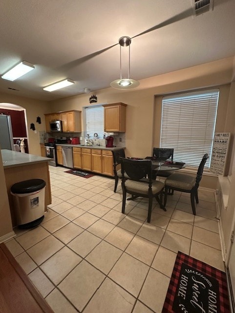 14602 Harcourt Bridge Ct, Houston, TX 77084 - kitchen with stainless steel appliances, light tile patterned floors, pendant lighting, arched walkways, and a sink