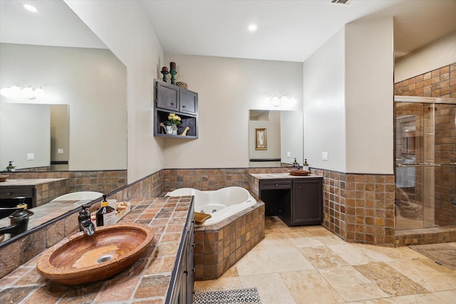 14111 Decker Dr, Magnolia, TX 77355 - bathroom with a tub with jets, a shower stall, two vanities, tile walls, and wainscoting