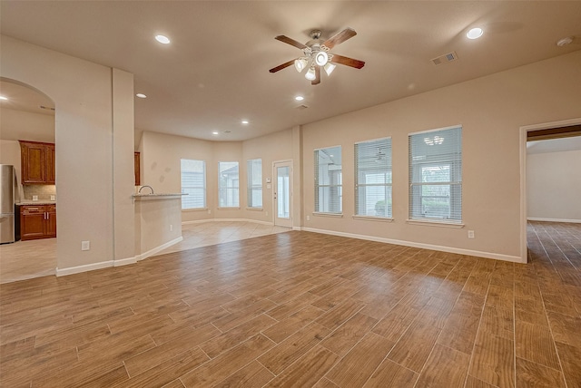 722 Silver Creek Cir, Richmond, TX 77406 - unfurnished living room featuring a ceiling fan, arched walkways, light wood-type flooring, baseboards, and recessed lighting