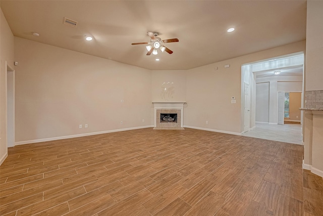 722 Silver Creek Cir, Richmond, TX 77406 - unfurnished living room featuring a tiled fireplace, ceiling fan, light wood finished floors, baseboards, and recessed lighting