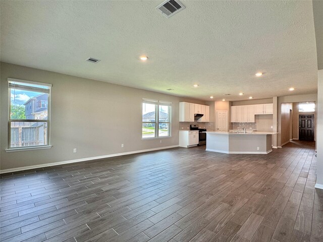2115 Katalonia Ln, Fresno, TX 77545 - unfurnished living room featuring dark wood-style flooring, a textured ceiling, recessed lighting, baseboards, and a sink
