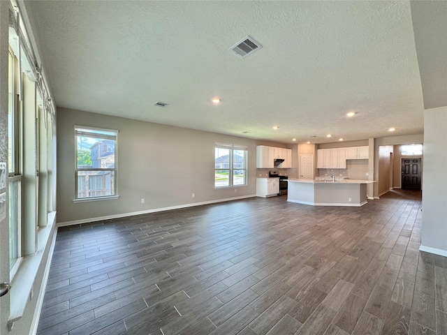 2115 Katalonia Ln, Fresno, TX 77545 - unfurnished living room with dark wood-style floors, recessed lighting, a textured ceiling, baseboards, and a sink