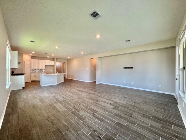 2115 Katalonia Ln, Fresno, TX 77545 - unfurnished living room with dark wood-style flooring, baseboards, recessed lighting, and a textured ceiling