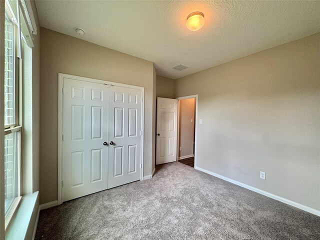 2115 Katalonia Ln, Fresno, TX 77545 - unfurnished bedroom featuring carpet flooring, baseboards, a closet, multiple windows, and a textured ceiling