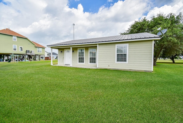 880 Swallow Dr, Palacios, TX 77465 - rear view of property with a lawn and a metal roof