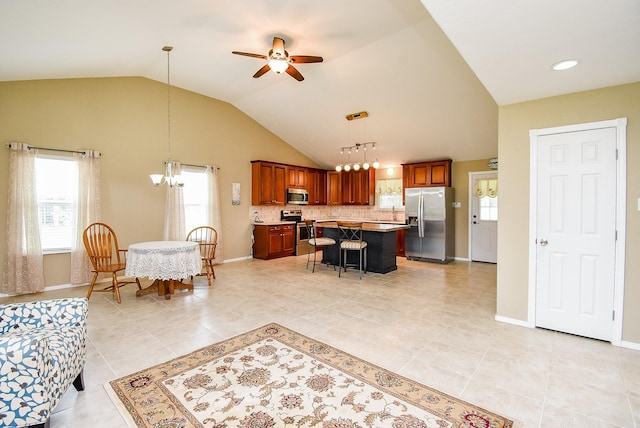 880 Swallow Dr, Palacios, TX 77465 - kitchen with stainless steel appliances, a chandelier, a ceiling fan, brown cabinetry, and vaulted ceiling