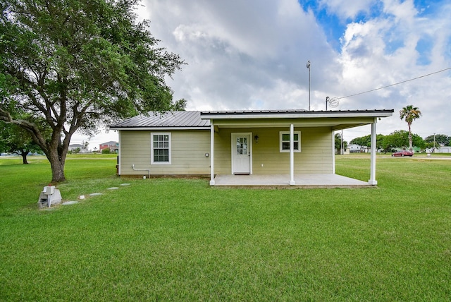 880 Swallow Dr, Palacios, TX 77465 - back of property featuring a lawn, a metal roof, and a patio