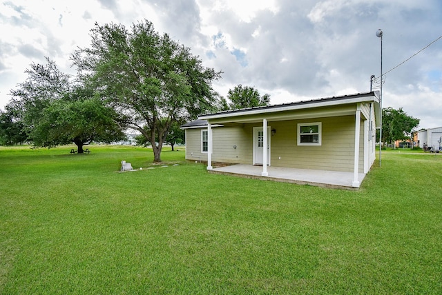 880 Swallow Dr, Palacios, TX 77465 - rear view of house with a patio area, a yard, and a metal roof