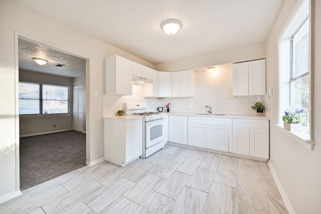 9306 Chesterfield Dr, Houston, TX 77051 - kitchen with white range with gas stovetop, a sink, under cabinet range hood, baseboards, and white cabinetry