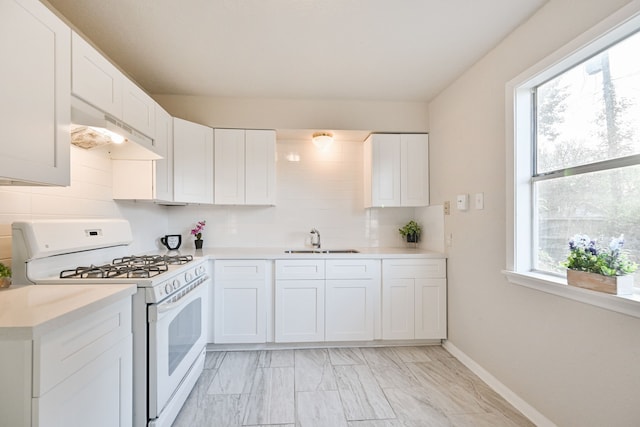 9306 Chesterfield Dr, Houston, TX 77051 - kitchen featuring white gas stove, under cabinet range hood, a sink, tasteful backsplash, and light countertops