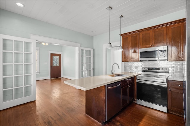 801 University Blvd, Galveston, TX 77550 - kitchen with stainless steel appliances, a sink, a peninsula, backsplash, and dark wood-style floors