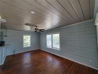 801 University Blvd, Galveston, TX 77550 - unfurnished living room with baseboards, wooden ceiling, wood finished floors, and a chandelier
