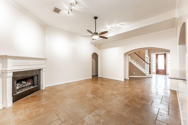 12515 Country Arbor Ln, Houston, TX 77041 - unfurnished living room with arched walkways, stone tile flooring, a ceiling fan, a tile fireplace, and ornamental molding
