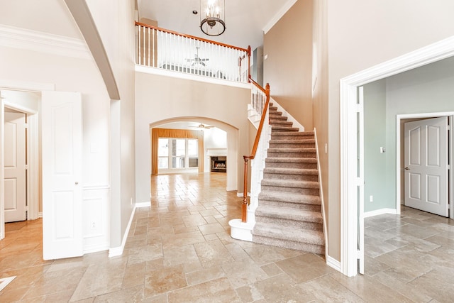 12515 Country Arbor Ln, Houston, TX 77041 - stairs featuring arched walkways, stone tile flooring, baseboards, a fireplace, and a towering ceiling