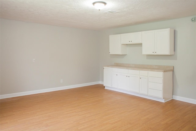 912 Robinson Rd, La Porte, TX 77571 - kitchen featuring light wood-style flooring, a textured ceiling, white cabinets, baseboards, and light countertops