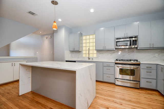 8642 Meadowcroft Dr, Houston, TX 77063 - kitchen with stainless steel appliances, gray cabinets, a sink, backsplash, and a center island